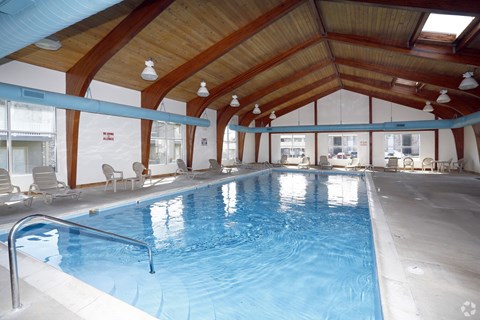 A large indoor swimming pool with a wooden ceiling and white walls.