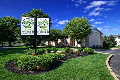 Two signs reading "The Park at Greenhill" stand in front of a building.