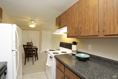 A kitchen with a black counter top and wooden cabinets.