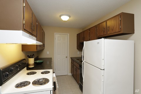 A kitchen with a white stove and a white refrigerator.