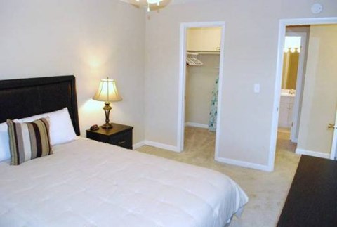 A bedroom with a large bed and a lamp on a side table.