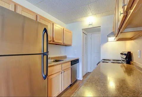 A kitchen with a refrigerator, cabinets, and a counter.
