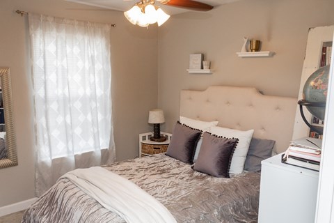 A bedroom with a bed, nightstand, and a ceiling fan.