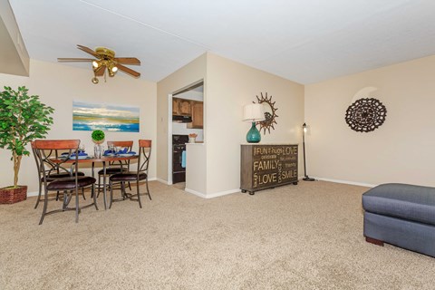 A living room with a dining table and chairs, a sofa, and a ceiling fan.