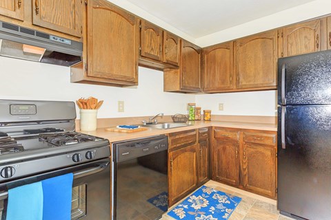 A kitchen with wooden cabinets and a black refrigerator.