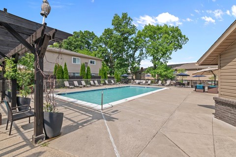 A pool area with a patio and a few chairs.