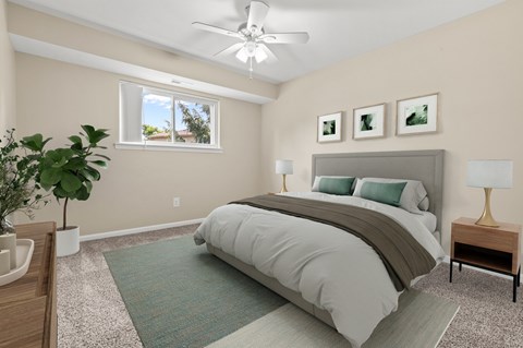 A bedroom with a large bed, a ceiling fan, and a potted plant.