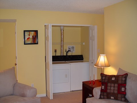 A living room with a grey couch, a brown pillow and a lamp.