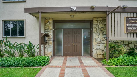 The front of a building with a brown door and a sign that reads "Sunset Manor Assisted Living.".