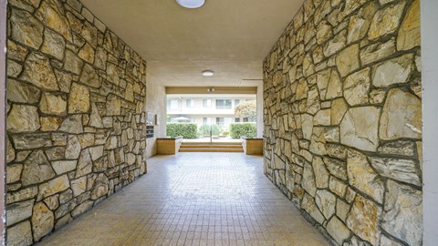 A long hallway with stone walls and a tiled floor.