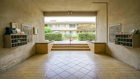 A hallway with a tiled floor and a view of a building through a window.