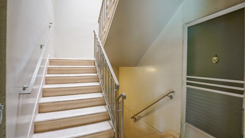 A staircase with a metal railing and wooden steps leading to a door with a glass panel.