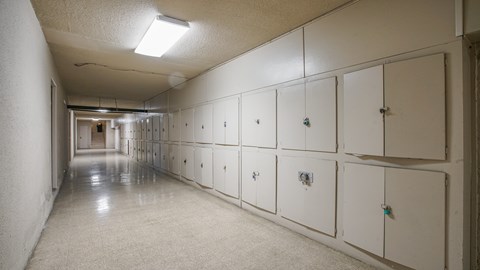 A long hallway with white lockers on the wall.