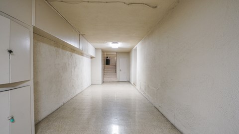 A long, narrow hallway with a staircase in the distance.