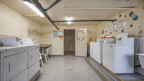 A clean, empty industrial kitchen with white appliances and a yellow line on the floor.