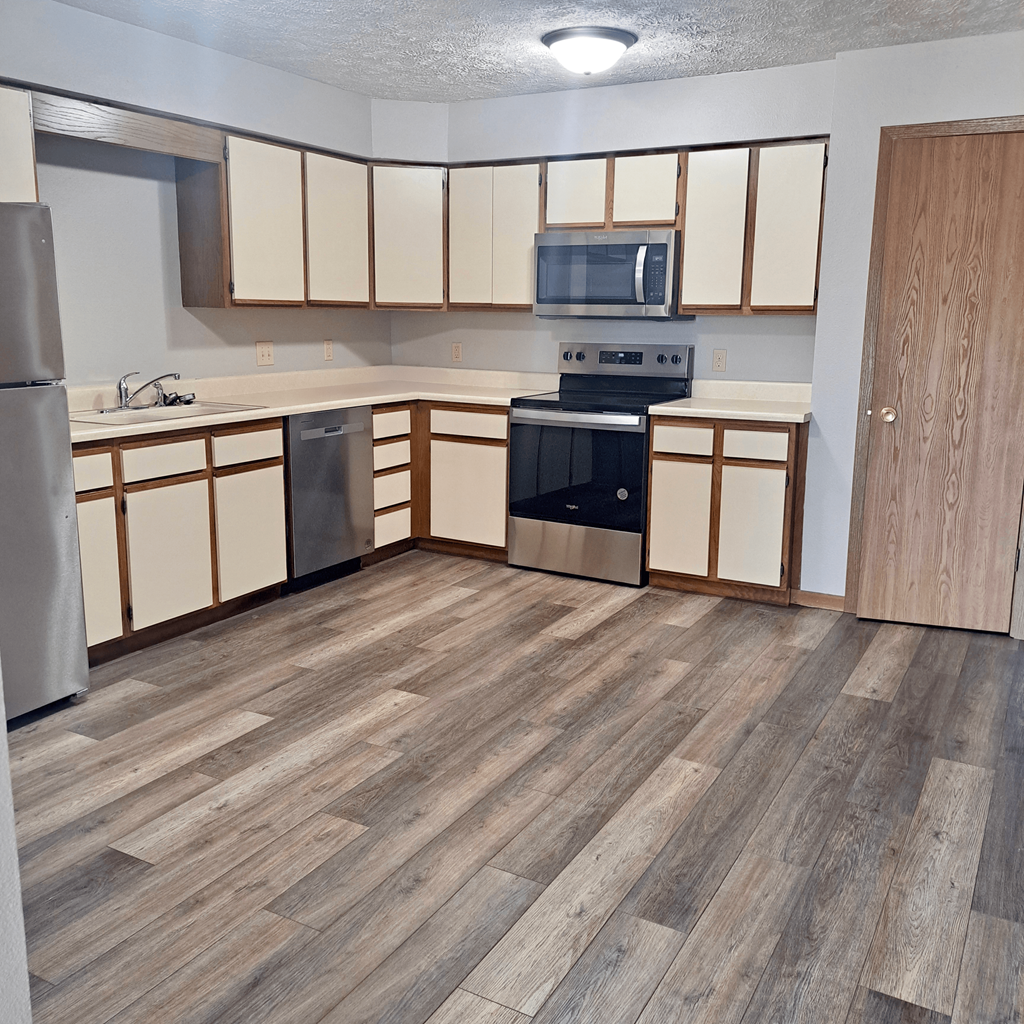 an empty kitchen with wood flooring in an apartment