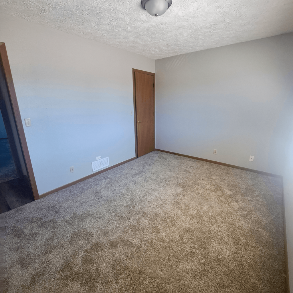 an empty living room with white walls and carpet