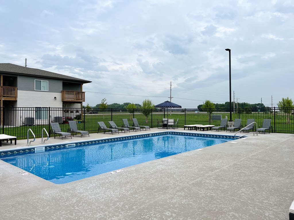 a swimming pool with chairs around it in front of a house