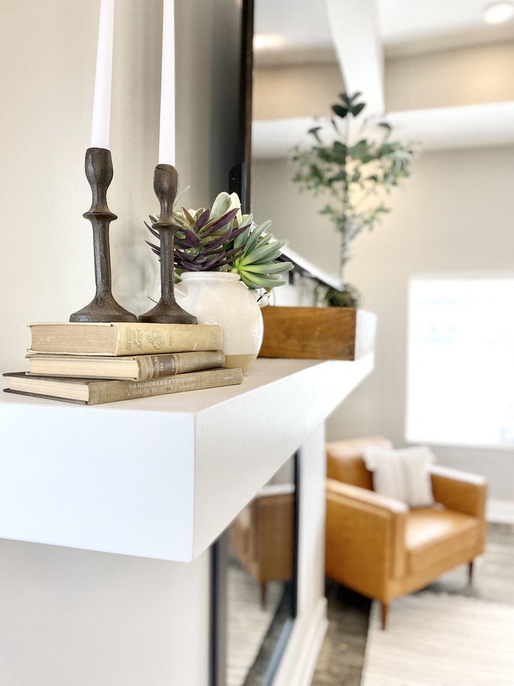 a mantel filled with books and a vase on top of a white shelf