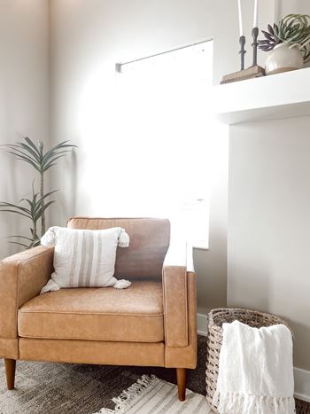 a leather chair in a living room with a white blanket and pillows