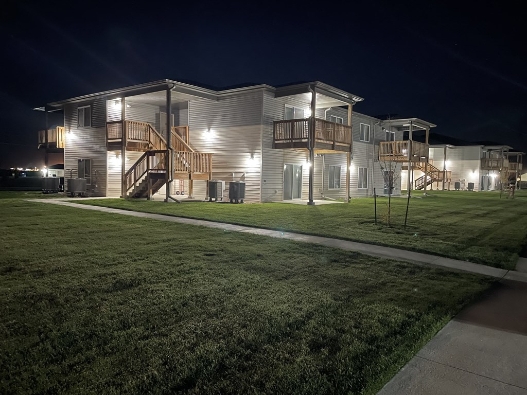a large white house at night with a yard and stairs