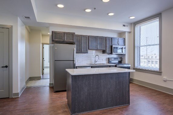 A kitchen with a refrigerator, microwave, and oven.