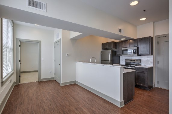 A kitchen with a white counter and brown flooring.