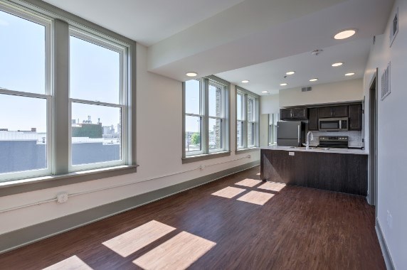 A spacious room with wooden floors and large windows.