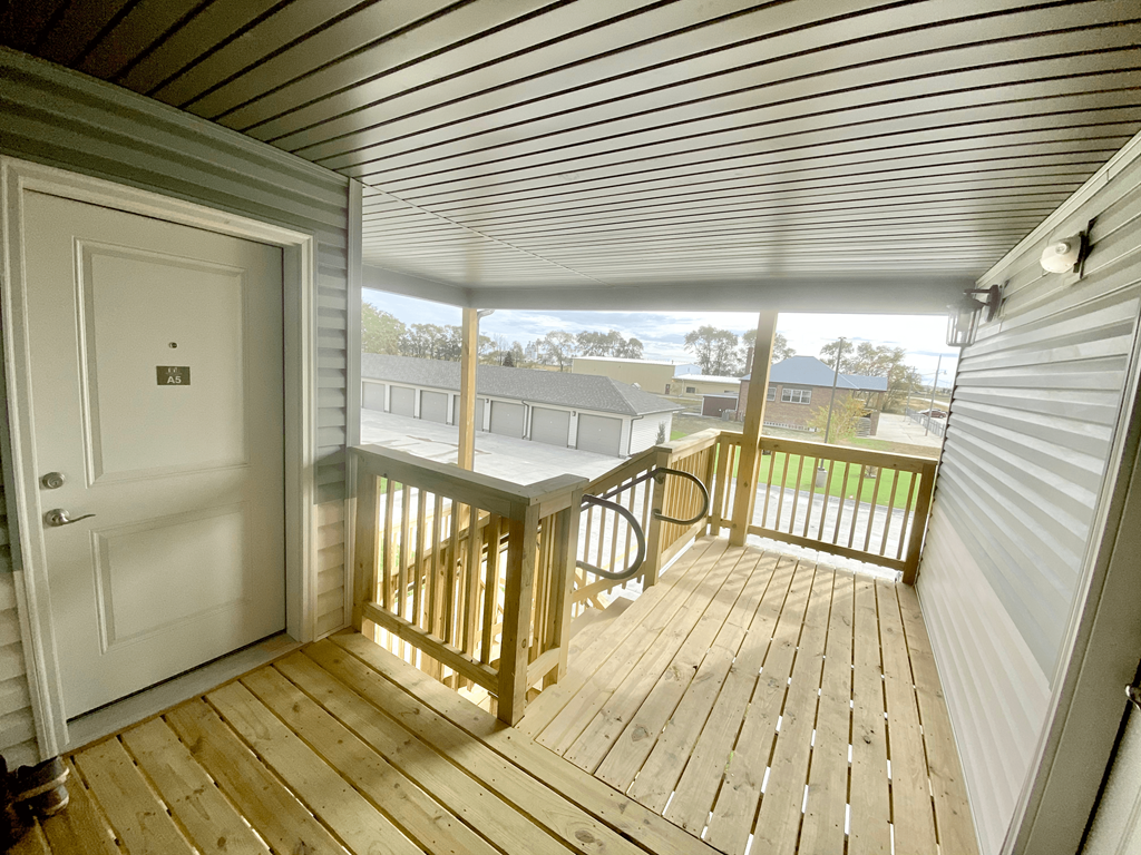 the deck of a home with a white door and a wooden railing