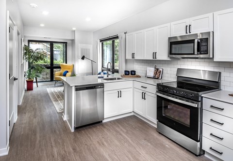 A modern kitchen with white cabinets and stainless steel appliances.