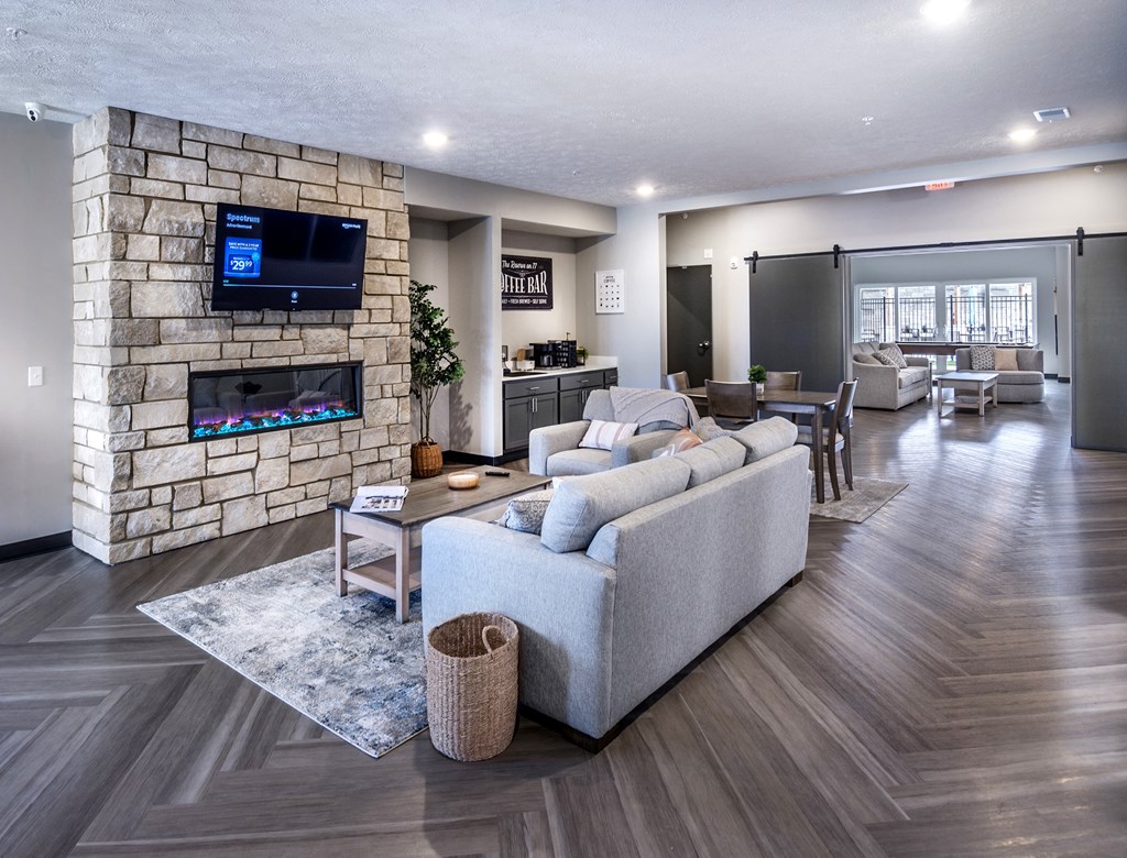 A modern living room with a stone wall and a large grey sofa.