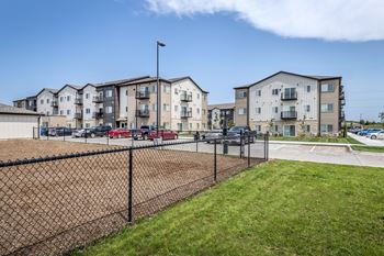 A row of modern apartment buildings with a black fence in the foreground.