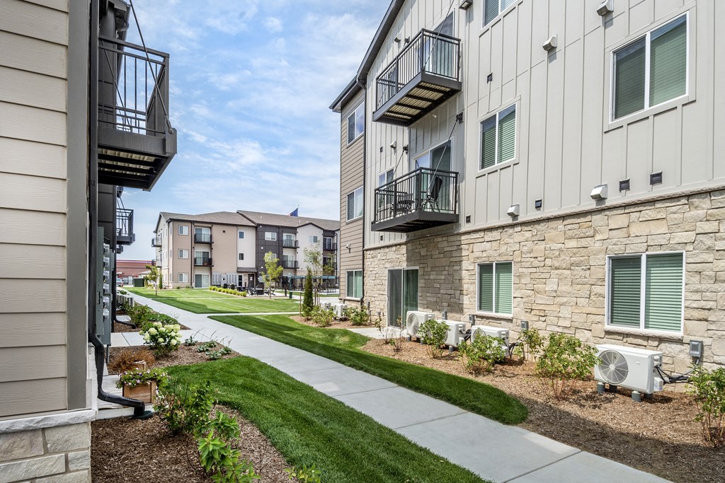 A row of apartment buildings with balconies and landscaping.