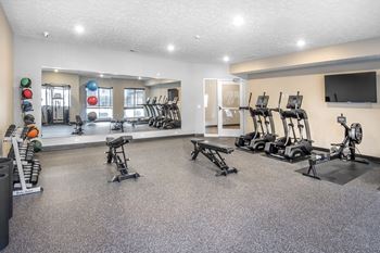 A gym with a variety of equipment including treadmills, weights, and exercise machines.