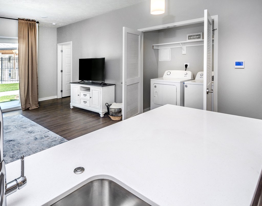 A modern kitchen with a white countertop and a stainless steel sink.