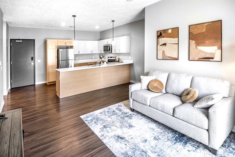 A modern living room with a white couch and a kitchen area in the background.