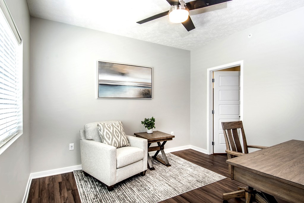 A living room with a white couch, a wooden coffee table, and a painting on the wall.