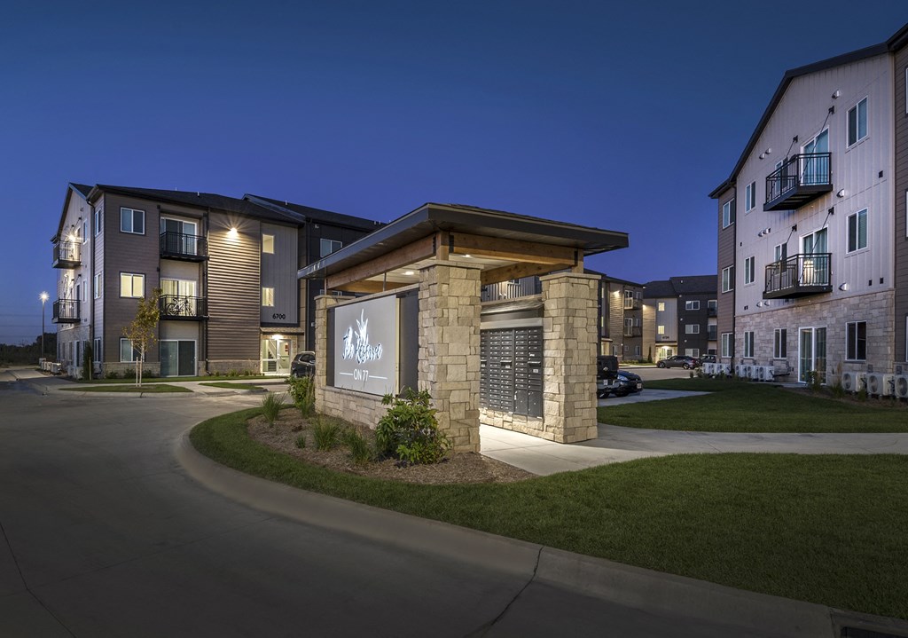 A building with a sign that says "The Woodlands Apartments" is lit up at night.