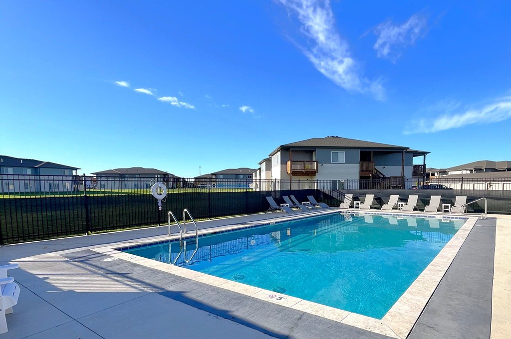 a swimming pool with chairs around it in front of a house