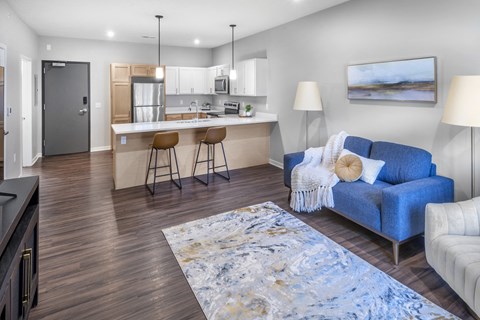 A blue sofa sits in a living room with a kitchen in the background.