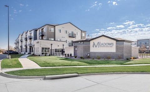 The Meadows apartment complex is a modern building with a spacious front lawn.