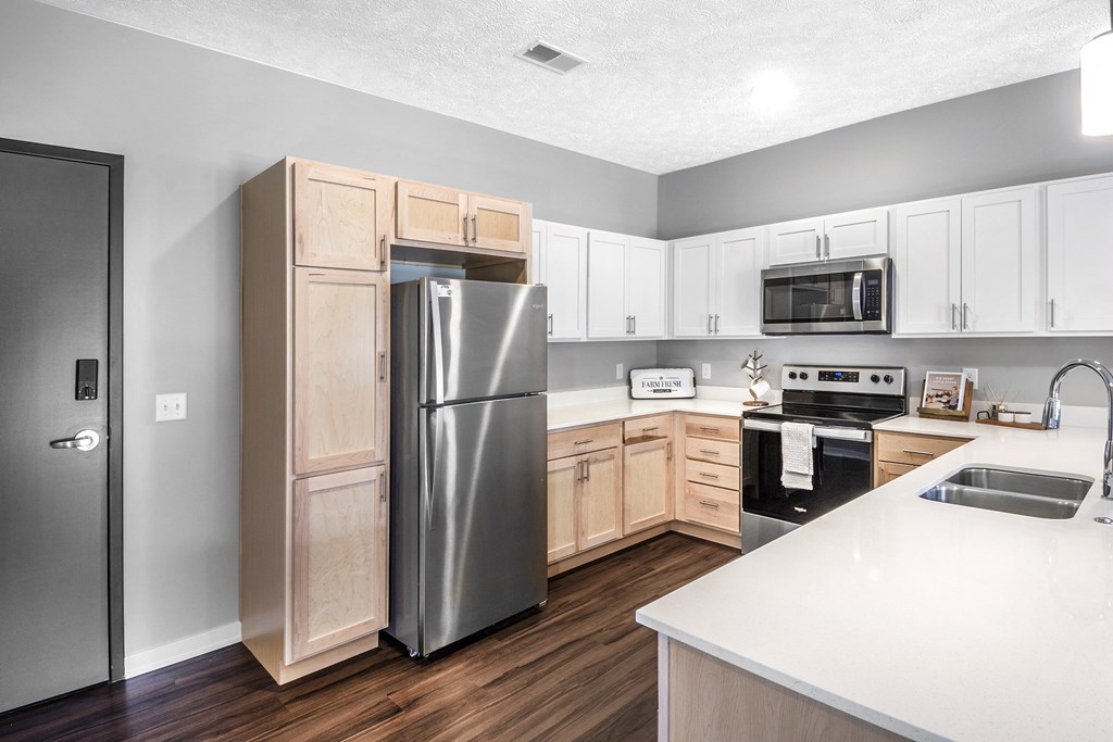A kitchen with a refrigerator, microwave, oven, and sink.