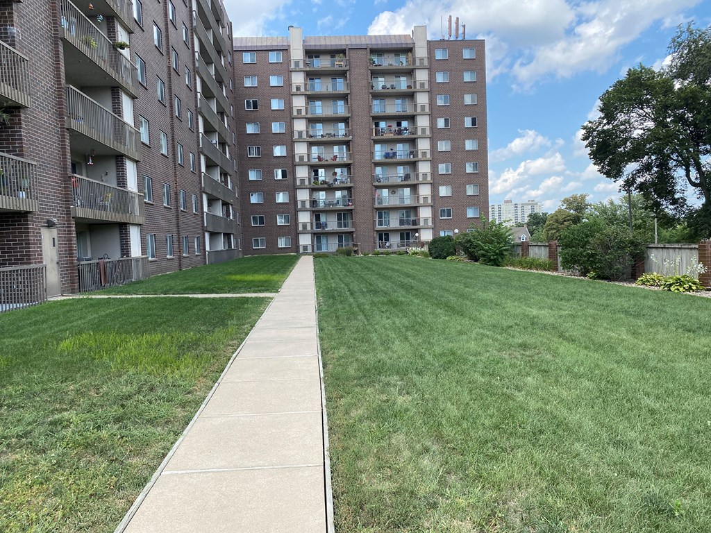 Facade of the building, highlighting the exterior structure, windows, and clean lines, with greenery around the base.