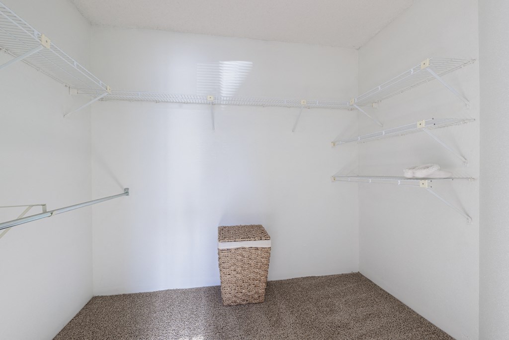 a walk in closet with white walls and a basket in the corner