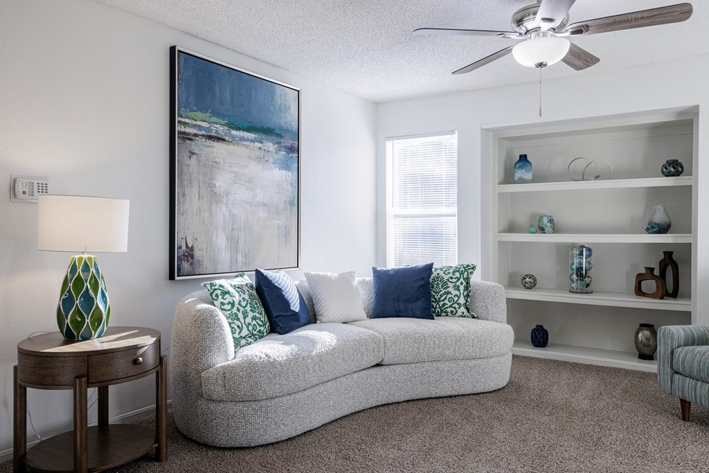 A spacious living room in the model unit of Skyler Ridge Apartments, with a comfortable couch and ceiling fan.