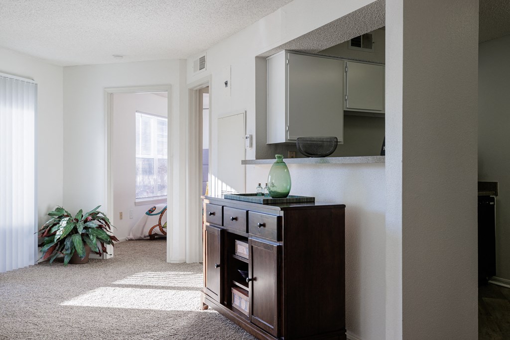 a living room with a dresser and a mirror on the wall