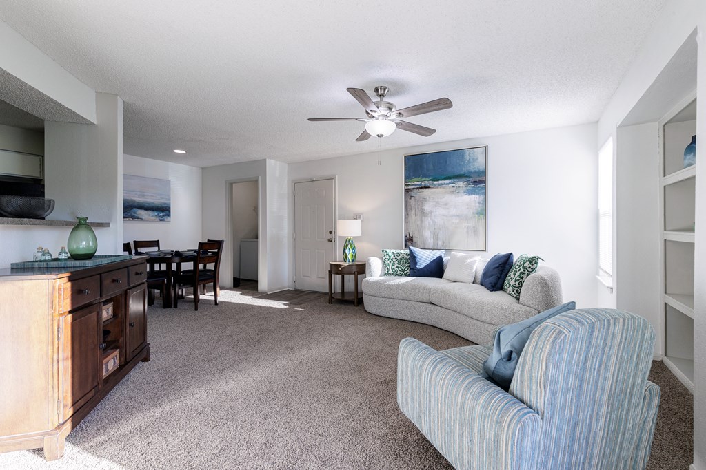 a living room with a couch and a chair and a ceiling fan