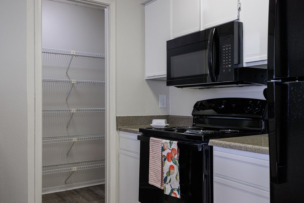 a kitchen with a stove and microwave and a walk in closet
