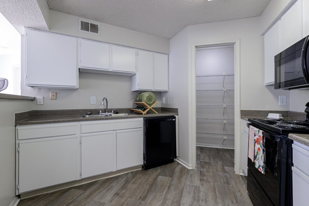 a kitchen with white cabinets and a black dishwasher and a sink