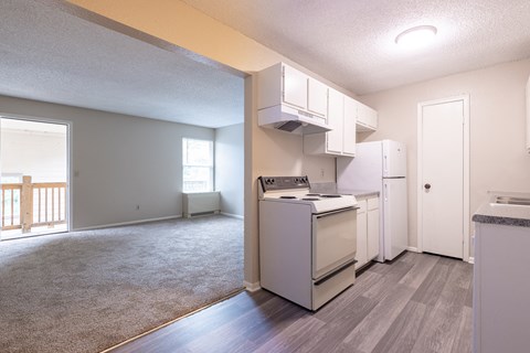 A kitchen with white appliances and a grey floor.